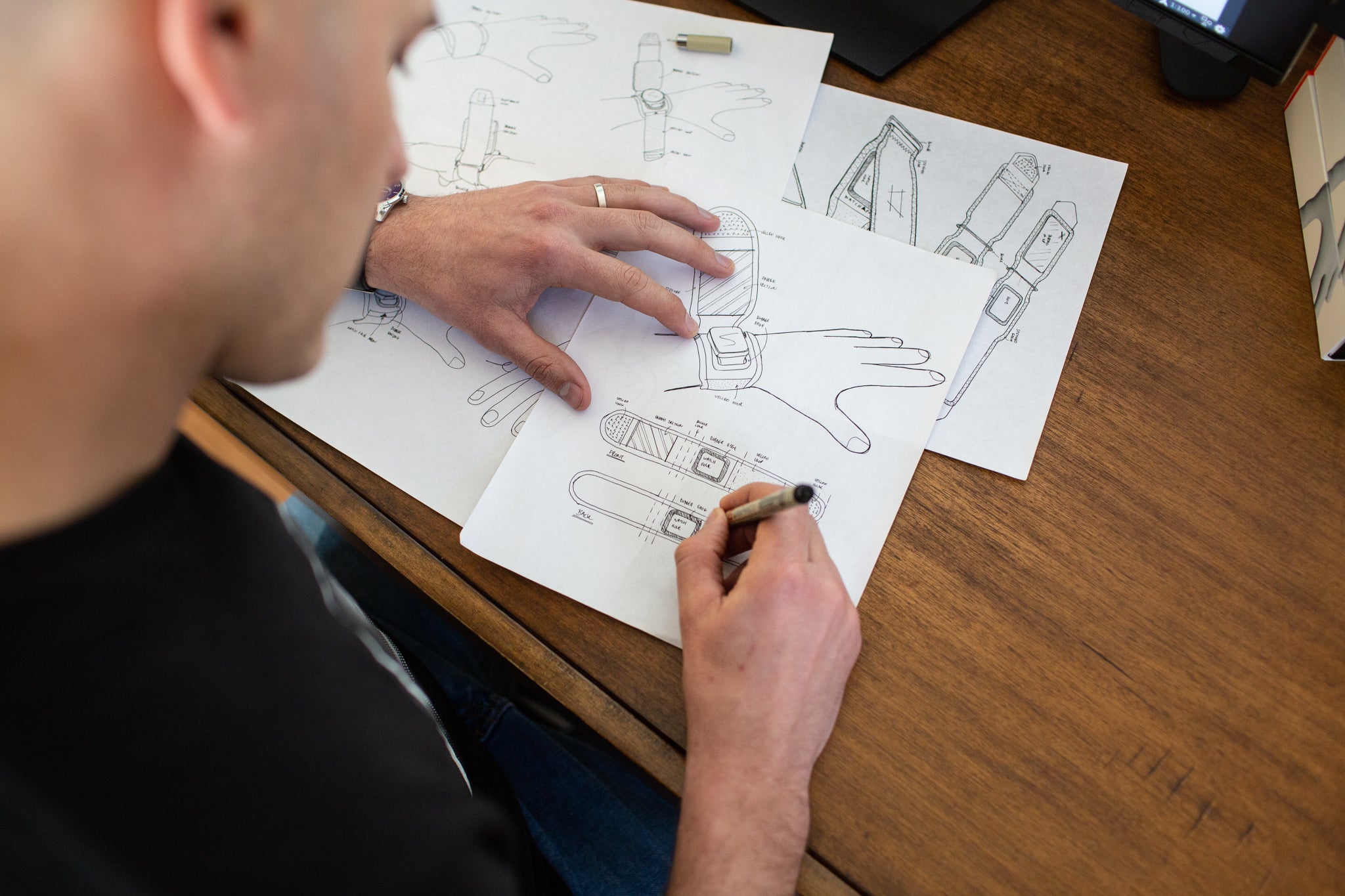 Person working on technical drawings of a hand at a desk