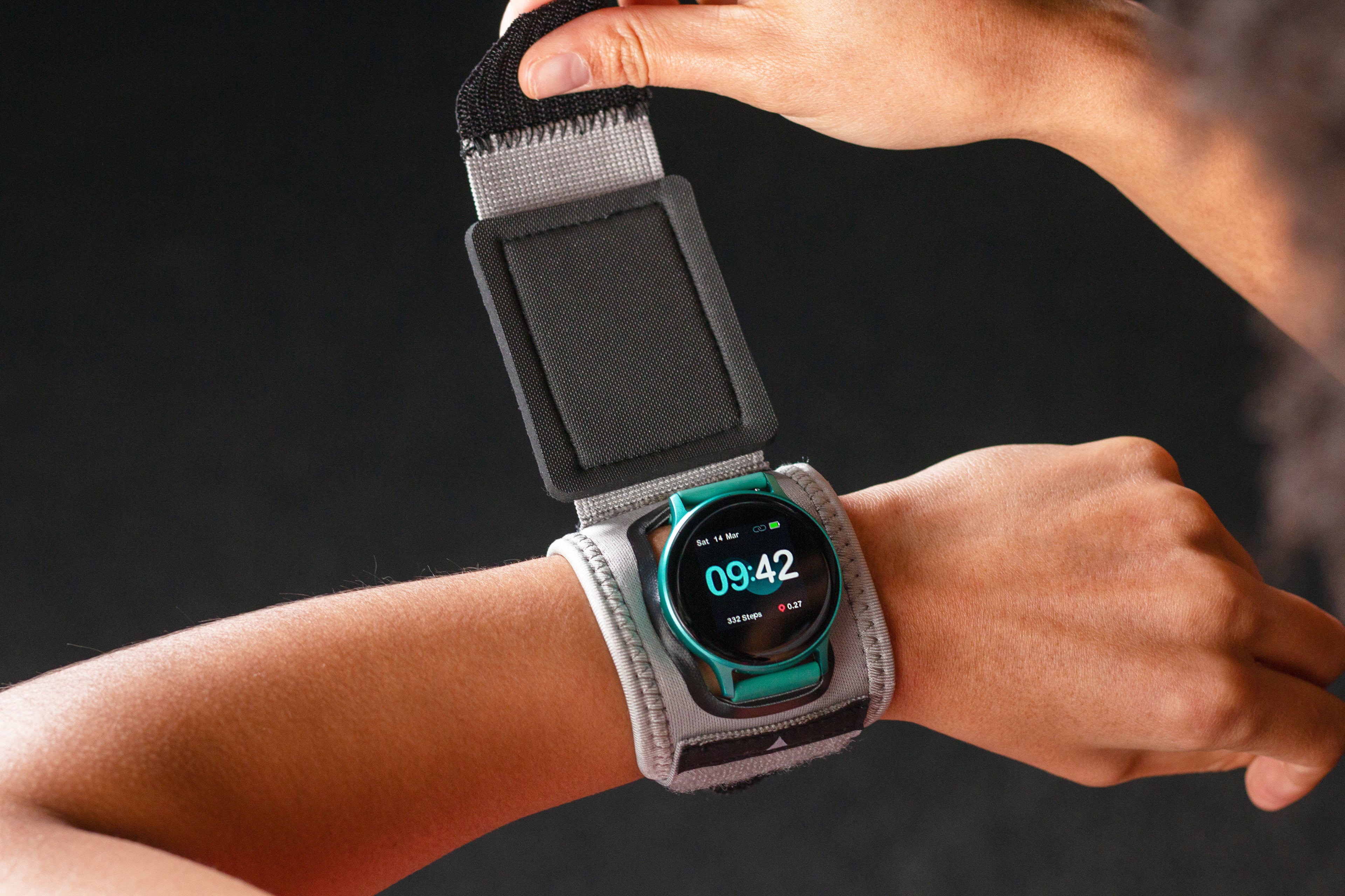 Smartwatch with a gray strap being worn on a wrist against a black background